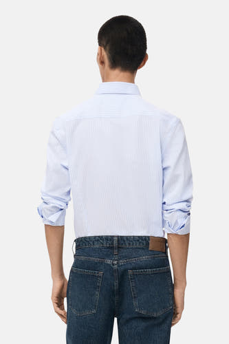 Chemise bleue rayée avec manches longues de MANGO, vue de derrière avec des jeans bleu marine.