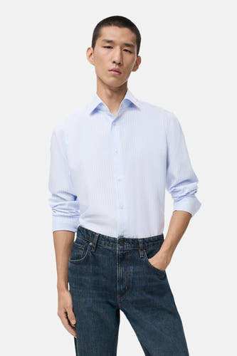 Chemise rayée bleue de MANGO avec longues manches, portée avec des jeans foncés.