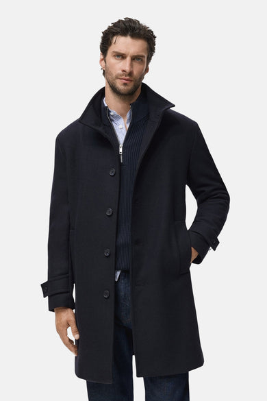 Manteau long bleu de MANGO, vu de l'arrière, avec des jeans bleus foncés et des chaussures marron.
