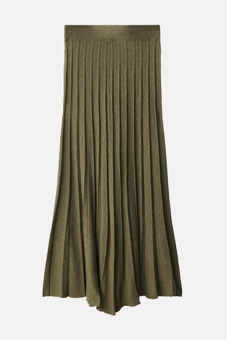 Long pantalon kaki de MANGO, texture froissée, associé à une chemise verte et des gants en cuir noirs.