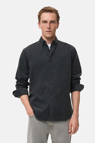Chemise grise à manches longues de MANGO, vue de derrière, avec des manches retroussées et un jeans gris.