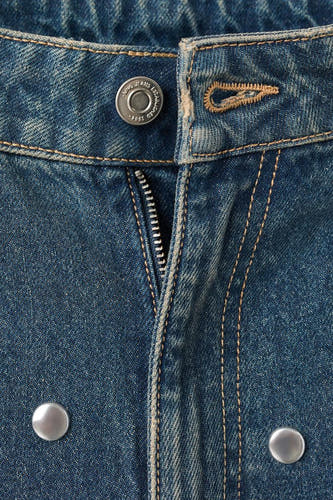 Jean en denim bleu de MANGO, avec une fermeture à glissière et des boutons métalliques.