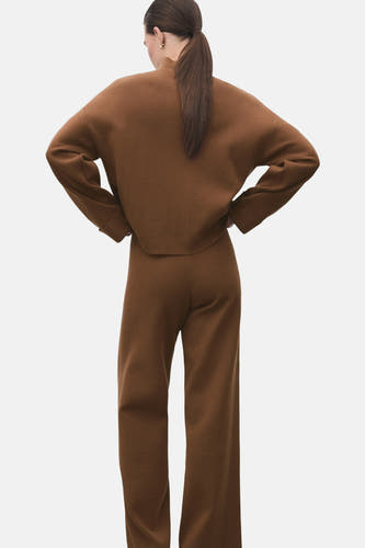 Bruine trui met rolkraag van MANGO, gezien van achteren met een bijpassende broek en een paardenstaart.
