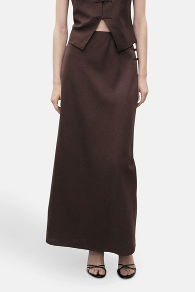Long manteau brun de MANGO, avec une coupe droite et des détails de nœud subtils.