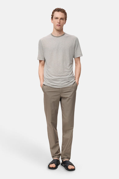 Pantalon marron de MANGO, porté avec un t-shirt rayé et des sandales noires.