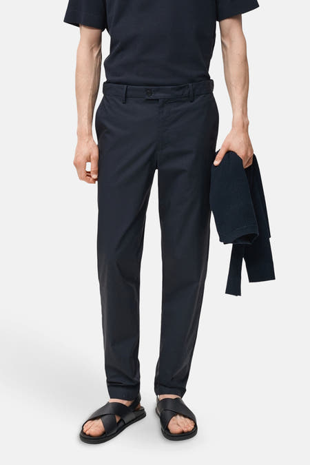 Pantalon bleu de MANGO, porté avec un t-shirt bleu et des sandales noires.
