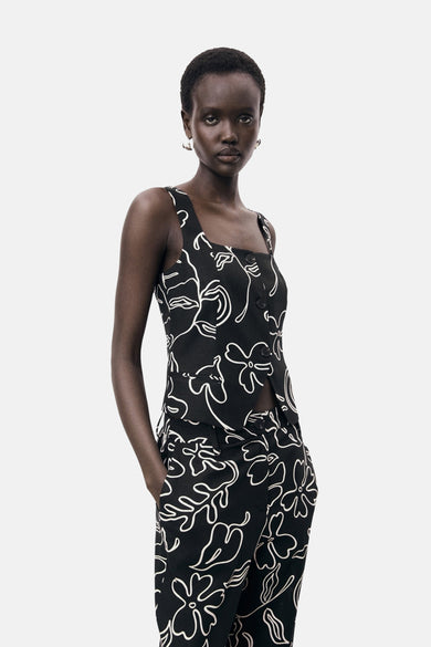 Blouse sans manches noire de MANGO, avec imprimé de fleurs blanches et fermeture à boutons.