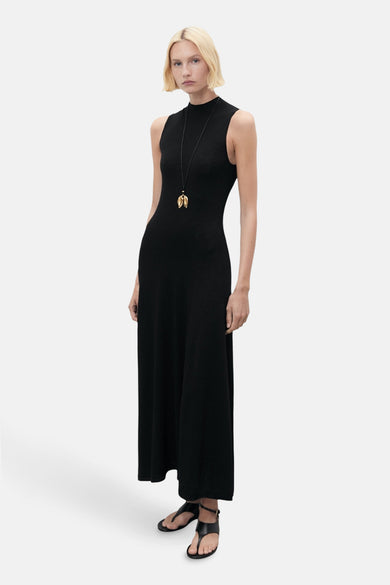 Robe sans manches noire de MANGO, avec une longue chaîne d'or et des sandales noires.