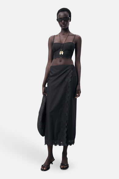 Robe longue noire de MANGO, avec des détails sur les côtés et un col, associée à une chemise noire et une chaîne.