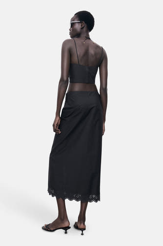 Longue jupe noire de MANGO, avec broderie sur l'ourlet, vue de derrière.