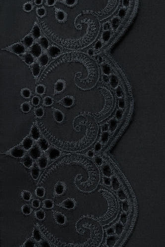 Longue jupe noire de MANGO, avec un détail de broderie anglaise raffiné à la base.