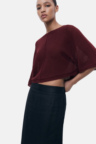 Veste Bordeaux avec col rond de MANGO, portée avec une jupe noire.
