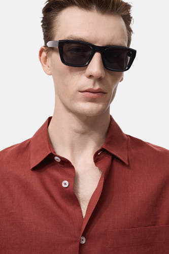 Rouge, chemise en lin à manches longues de MANGO, portée ouverte et avec un chapeau de soleil.