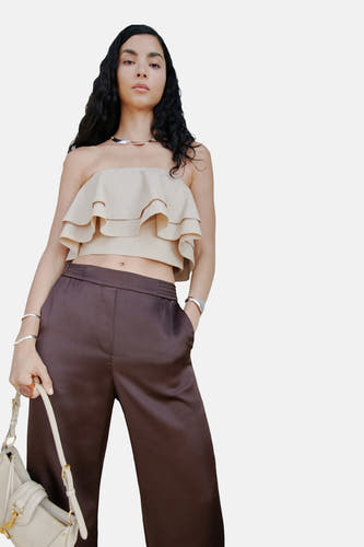 Pantalon marron de MANGO, porté avec un haut beige et une sacoche.