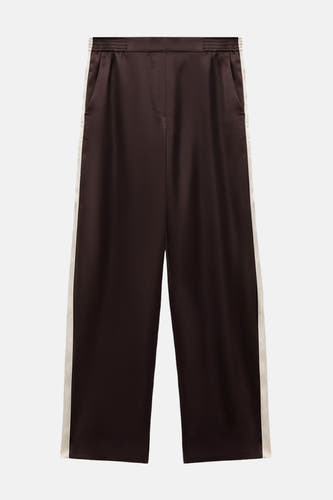 Pantalon marron de MANGO avec une ceinture élastique et un revers blanc sur le côté.