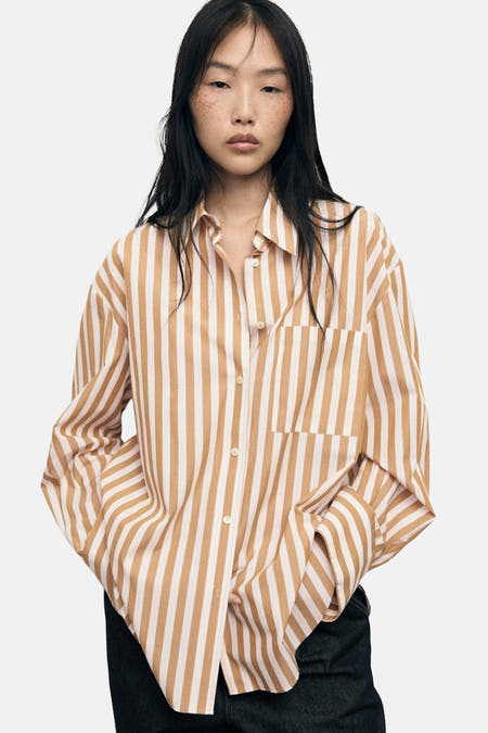 Chemise multicolore à manches longues de MANGO, avec des rayures verticales, portée avec des jeans larges foncés et des talons noirs.