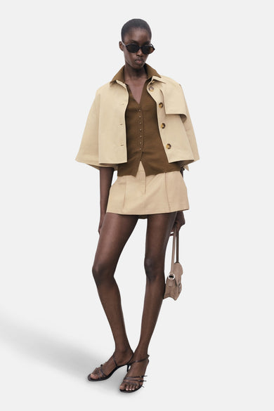 Kaki polo avec des manches courtes de MANGO, porté avec un blouson beige et une jupe coordonnée.