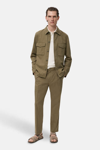 Chemise verte à longues manches de MANGO, avec des poches broiquées, associée à un polos blanc et un pantalon kaki.