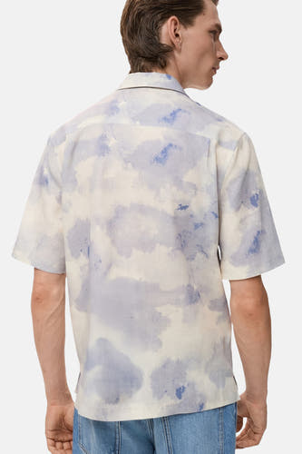 Chemise multicolore à manches courtes de MANGO, avec un motif àquarel et portée avec un jean bleu.