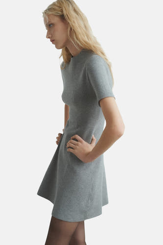Vêtement gris à manches courtes de MANGO, vu de côté, avec une taille cintrée et une jupe qui tombe, porté avec des slips.