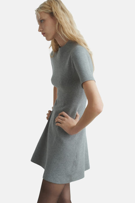 Vêtement gris à manches courtes de MANGO, vu de côté, avec une taille cintrée et une jupe qui tombe, porté avec des slips.