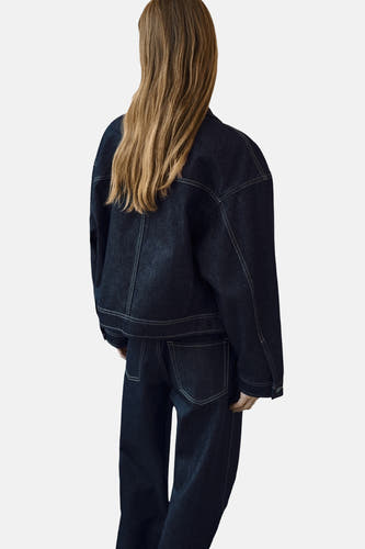 Manteau de jeans bleu marine de MANGO, vu de l'arrière avec des jeans coordonnés.