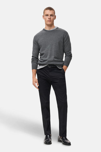 Sweat-shirt gris à col rond de MANGO, porté sur un chemisier blanc avec un pantalon noir et des loafers noirs.