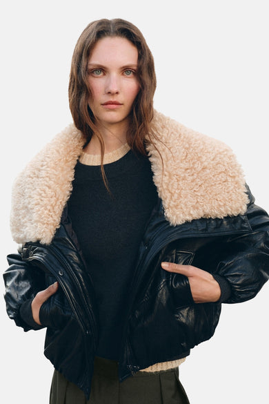 Manteau court noir de MANGO, avec une grande capuche en fausse fourrure douce et beige, à l'arrière.