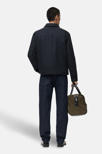 Manteau bleu court de MANGO, vu d'arrière, associé à des jeans foncés et un sac.