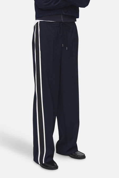 Pantalon bleu de MANGO avec des rayures blanches et noires sur les côtés, coupe décontractée et cordon de serrage.