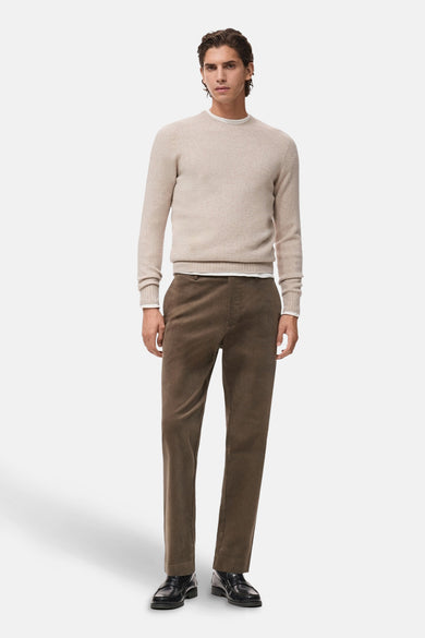 Beige ronde hals trui van MANGO, gedragen met een wit shirt en bruine corduroy broek, met zwarte leren schoenen.
