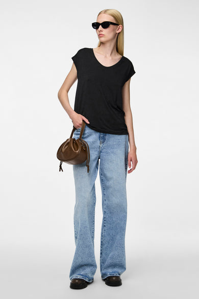 Zwart T-shirt van PIECES®, gedragen met wijde jeans, een bruine handtas en zwarte zonnebril.