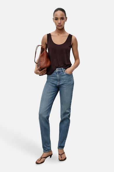 Jean-mère bleu marine de MANGO, associé à un t-shirt marron foncé et une sacoche en cuir tressé.