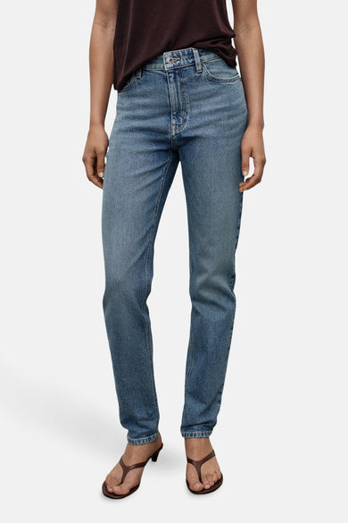 Jean mom bleu moyen de MANGO, porté avec des sandales brunes et un t-shirt marron foncé.