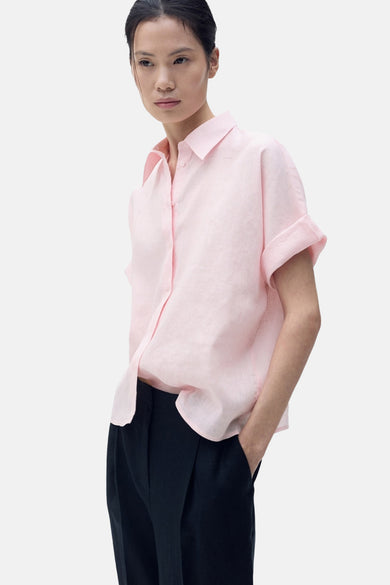 Chemise rose à manches courtes de MANGO, coupe décontractée et portée avec un pantalon noir.