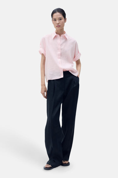 Chemise rose à manches courtes de MANGO, associée à un pantalon noir et des sandales.