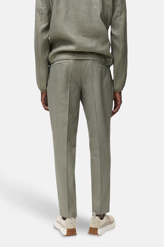 Pantalon kaki de MANGO, vu de arrière, combiné avec un blazer coordonné et des baskets beige.