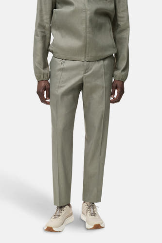 Pantalon kaki de MANGO, avec des plis et des chaussures d'une couleur neutre.