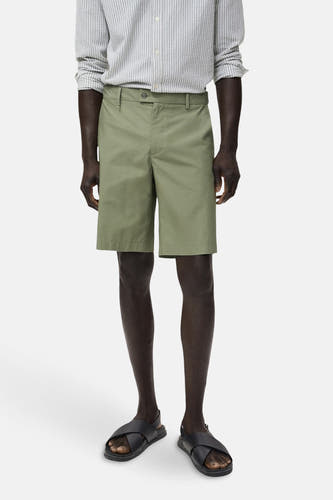 Short vert de MANGO, combiné avec un chemisier rayé et des sandales noires.