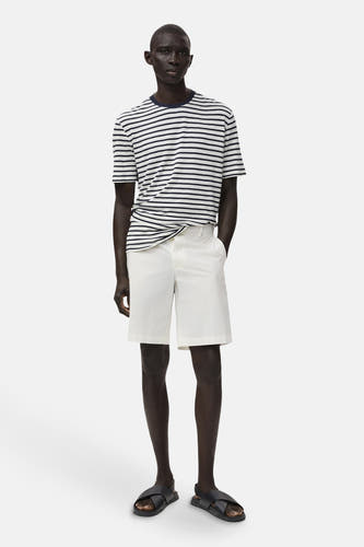 Short blanc de MANGO, associé à un t-shirt rayé et des sandales noires.