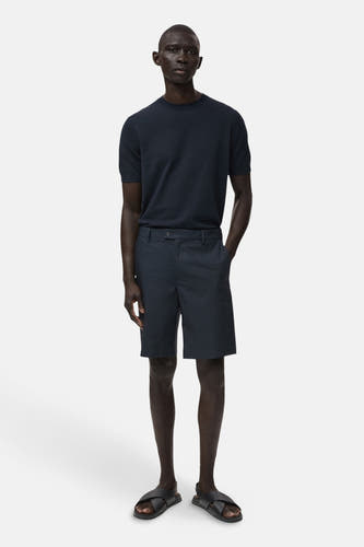 Short bleu de MANGO, porté avec un t-shirt bleu marine et des sandales noires.