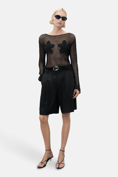 Sweat-shirt noir à col rond de MANGO, avec des applications florales et associé à des shorts noirs et des sandales.