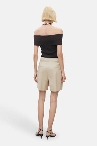 Shorts beige de MANGO, avec une taille haute et des poches arrière, portés avec un haut noir et des baskets.