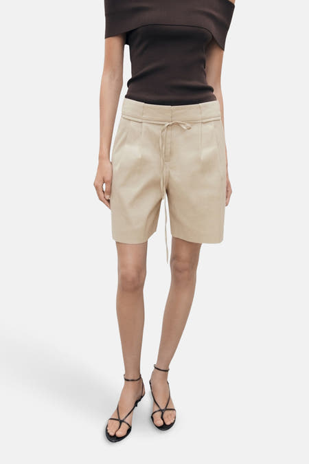 Shorts beige de MANGO, avec cordon, associés à une chemise brune et des sandales noires.
