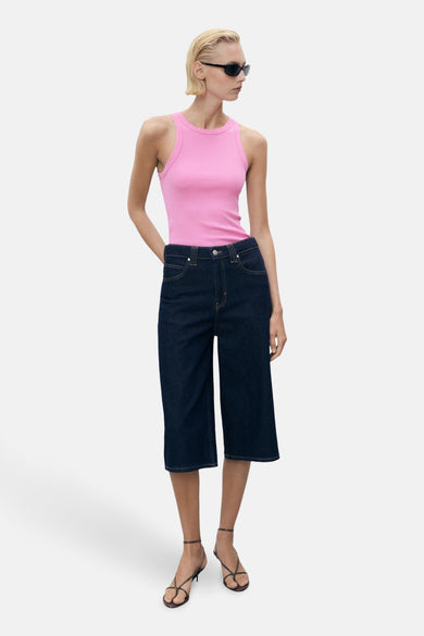 Maillot de corps rose de MANGO, porté avec des culottes de denim foncées et des sandales à brides.