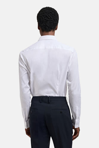 Blouse blanche à manches longues de MANGO, vue de derrière, associée à un pantalon foncé.