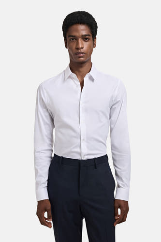 Blouse blanche à manches longues de MANGO, portée avec un pantalon foncé.