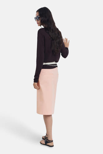Robe rose 3/4 de MANGO, avec une ceinture en chaîne à la taille et associée à un pull marron.