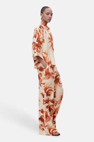 Pantalon multicolore de MANGO, avec un motif de feuille tropicale et des jambes larges, montré en vue latérale.
