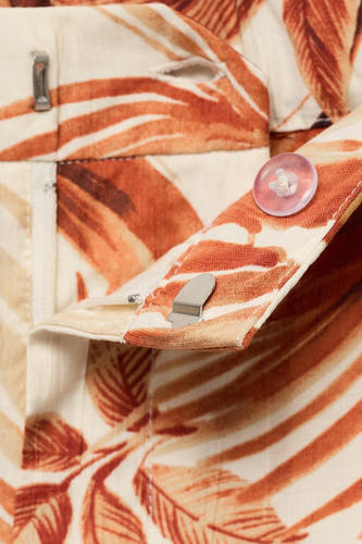 Pantalon multicolore de MANGO avec un motif de feuille tropicale et fermeture à boutons et à glissière.
